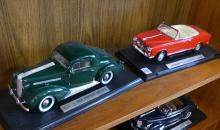 FOUR DIE-CAST CAR MODELS ON DISPLAY STANDS