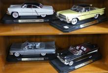 FOUR DIE-CAST CAR MODELS ON DISPLAY STANDS