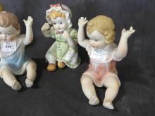 FOUR "PIANO BABY" FIGURINES